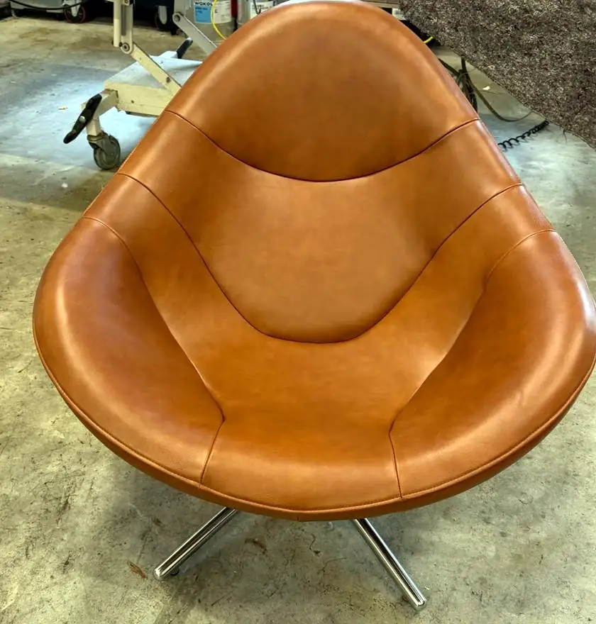 Ronde draaifauteuil met hoge rug in cognackleurig leer op een stervoet.
