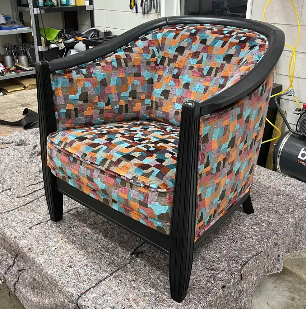Kuipfauteuil met een zwart gelakt houten frame, bekleed met een stof in een patroon van gekleurde driehoeken.