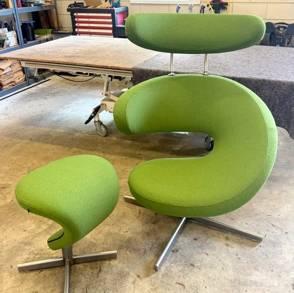 Gebogen loungestoel met hoofdsteun en losse poef, beide op een stervoet en bekleed in appelgroene stof.